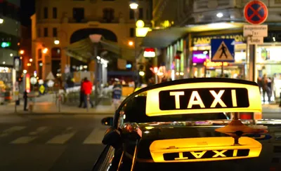 夜の街で光るタクシーの「TAXI」標示灯
