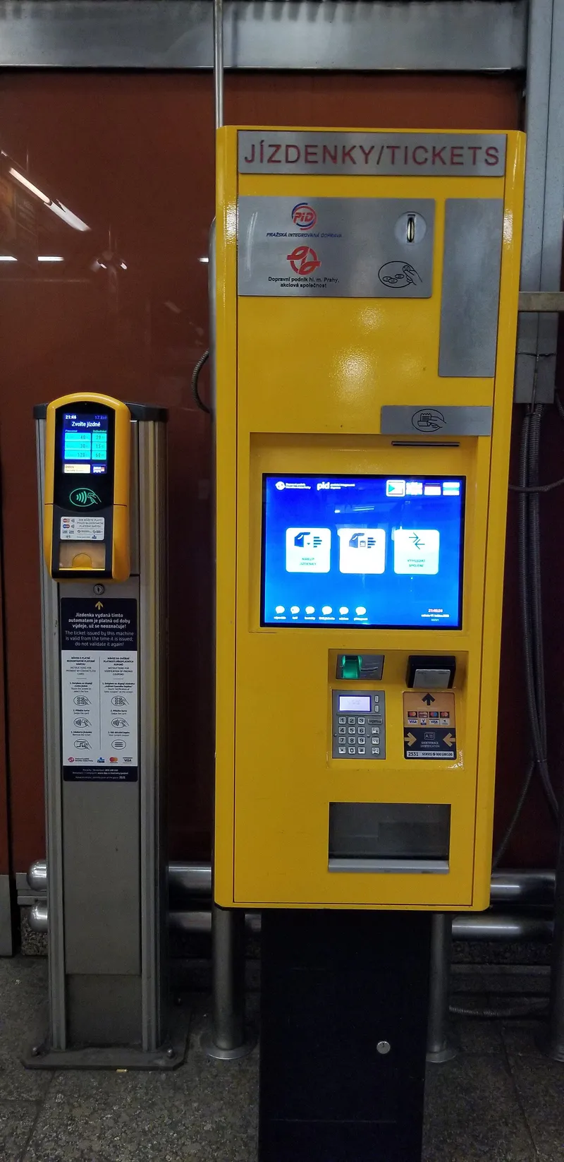 コンコースに並ぶ2種類の機械。右の大きな「JÍZDENKY/TICKETS」が硬貨とカードの券売機、左の細い柱が非接触カード専用の発券端末