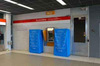 ルオホラハティ駅の入口。使用を止めた大型券売機には「切符の買い方」の覆いが掛かる——アプリ／ネットのHSLショップ／リーダーでのタッチ決済／販売所の4つ（2026年8月）