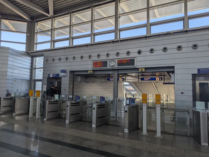 空港駅メトロの改札。ゲート脇の青い案内に「TRAVEL WITH YOUR BANK CARD AS YOUR TICKET」とある