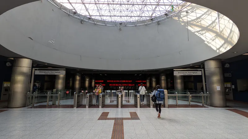 「Επικύρωση Εισιτηρίων／Ticket Validation」の下に並ぶ改札。ゲート上面のリーダーにタッチし、緑の↑が出ている通路を抜ける