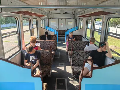 H5のHÉV車内。向かい合わせの座席が並ぶ古い車両で、窓の上には細い木製の網棚がある