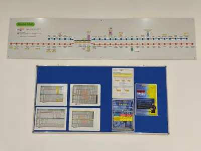 KTMコミューター駅の掲示板（セガンブ・ウタラ駅）。上が路線図、下の青いボードに紙の時刻表が貼ってある。本数が少ないので、降りた駅のこの掲示で帰りの時刻を控えておく