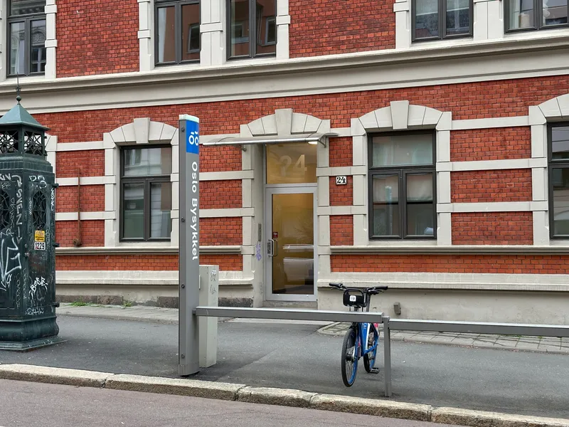 柱に縦向きで「Oslo Bysykkel」と書かれている場所がステーション（柱は灰色で、上端だけ青い）。柱の脇のラックに前輪を差して借り・返しする