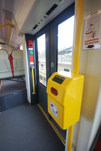 SKMの車内。ドア脇の黄色い刻印機に紙券を差し込む。壁の札は「KASOWNIK / VALIDATOR」