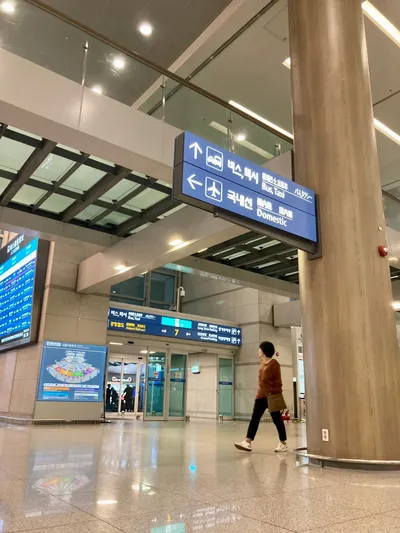 仁川空港第1ターミナルの到着階。頭上の案内が「버스, 택시（バス・タクシー）」と「국내선（国内線）」を示し、奥の出口帯には空港鉄道（공항철도）の表示も並ぶ。