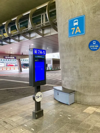 ターミナル前のバス乗り場。柱の「7A」とポールの「7A-5」が乗り場番号で、画面に次の便の系統番号が出る。
